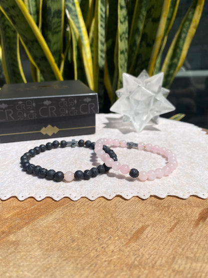 CR Casal | Par Quartzo Rosa e Lava Vulcânica com Cruz de Hematita – Paz, Amor e Proteção (Banho Ouro 18K)