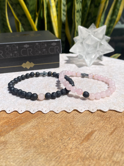 CR Casal | Par Quartzo Rosa e Lava Vulcânica com Cruz de Hematita – Paz, Amor e Proteção (Banho Ouro 18K)